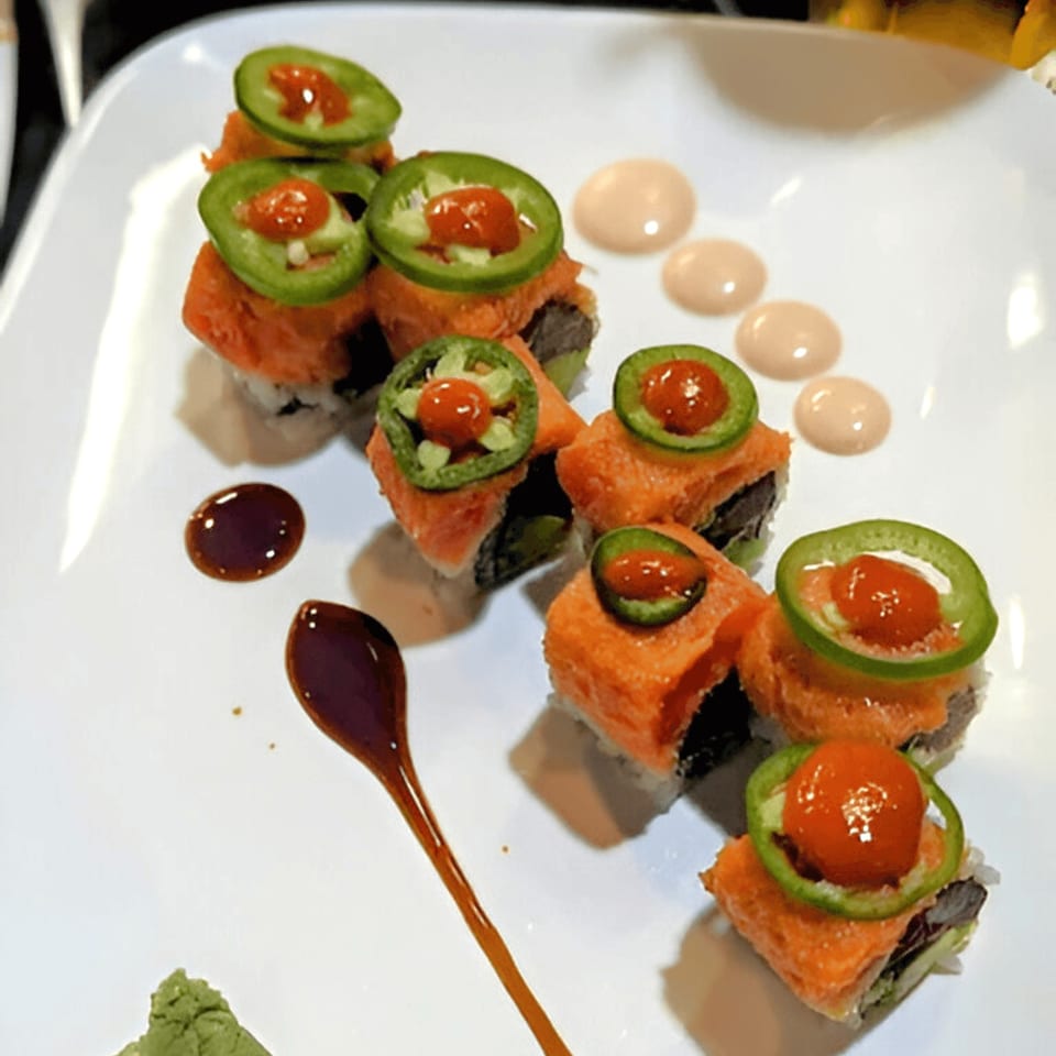 Corner Sushi's spicy salmon rolls topped with jalapeños and red sauce, with wasabi and soy sauce.