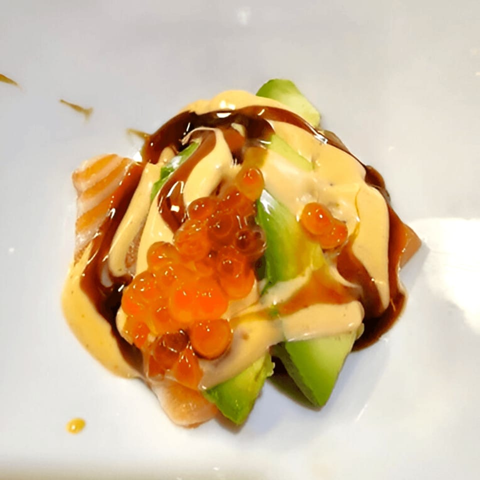 Corner Sushi's salmon and avocado salad with roe, drizzled with creamy and dark sauces.